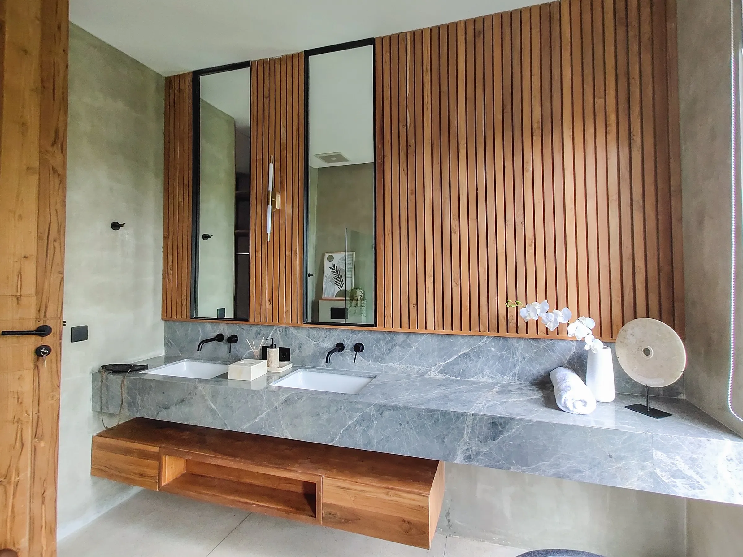 Floor-to-ceiling slatted teak panelling with a floating teak vanity and framed mirrors.