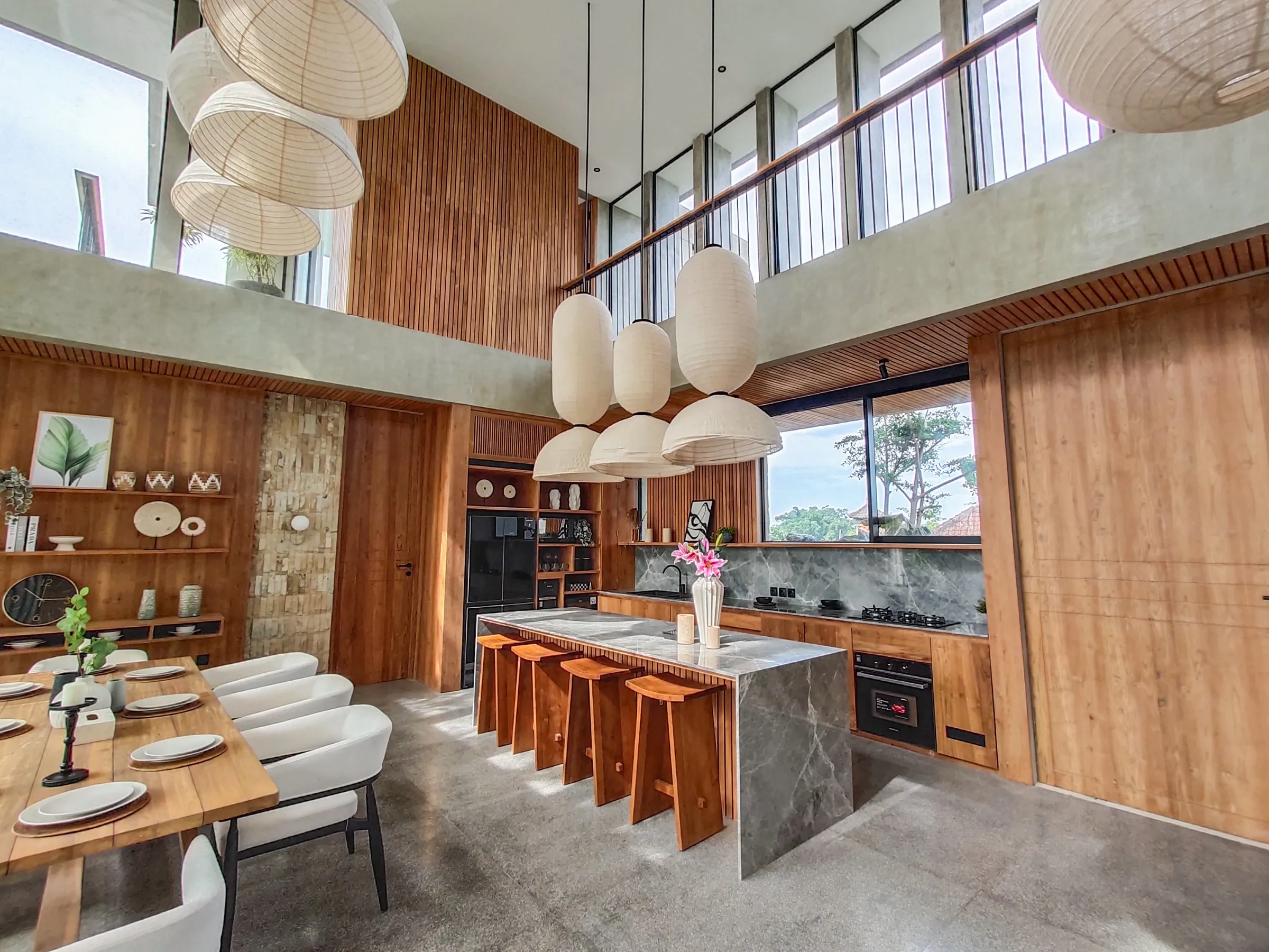 Tall kitchen joinery, teak island and dining table in the double-height living area.
