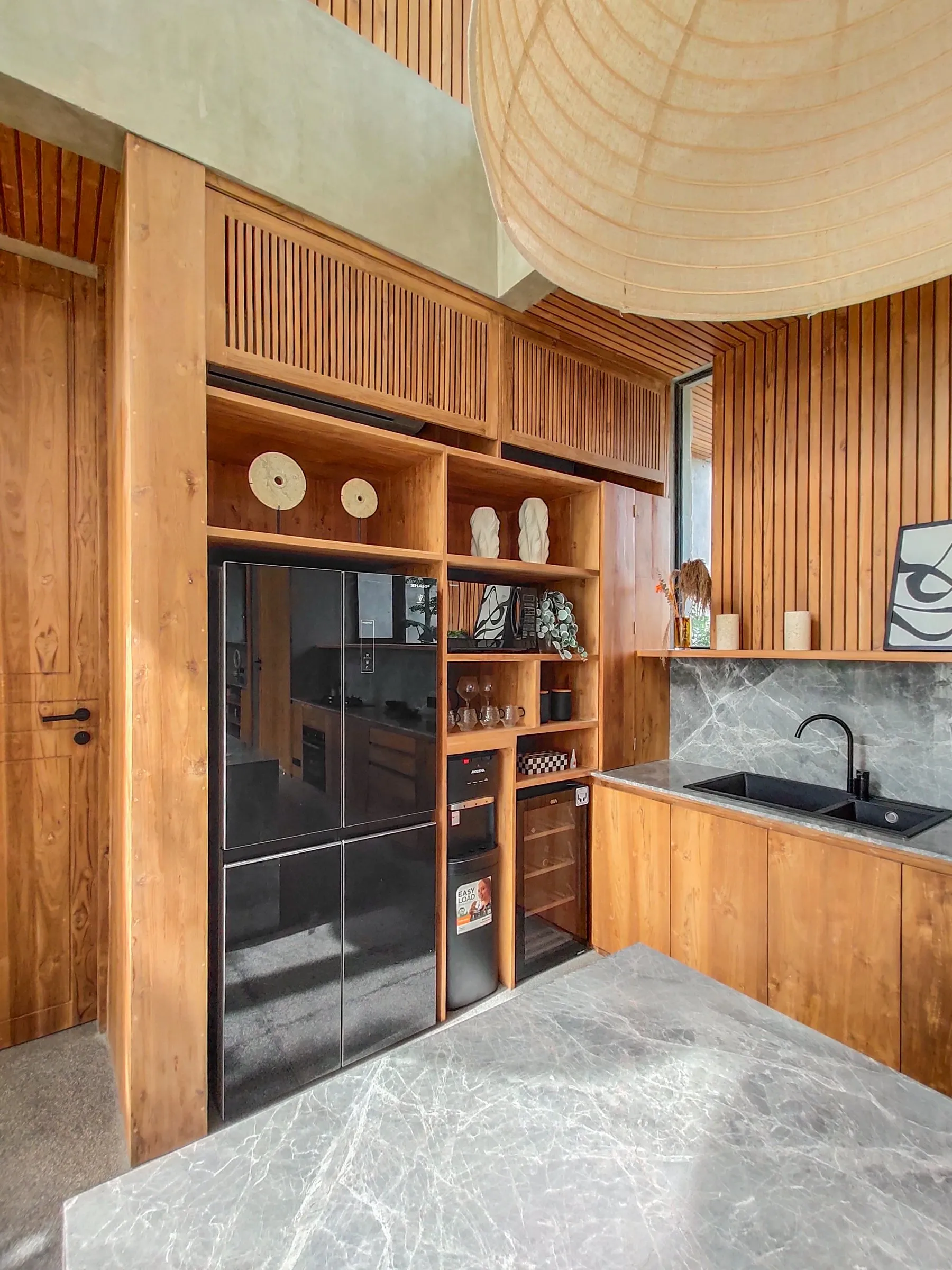 Floor-to-ceiling teak kitchen joinery with open shelving and integrated appliances.