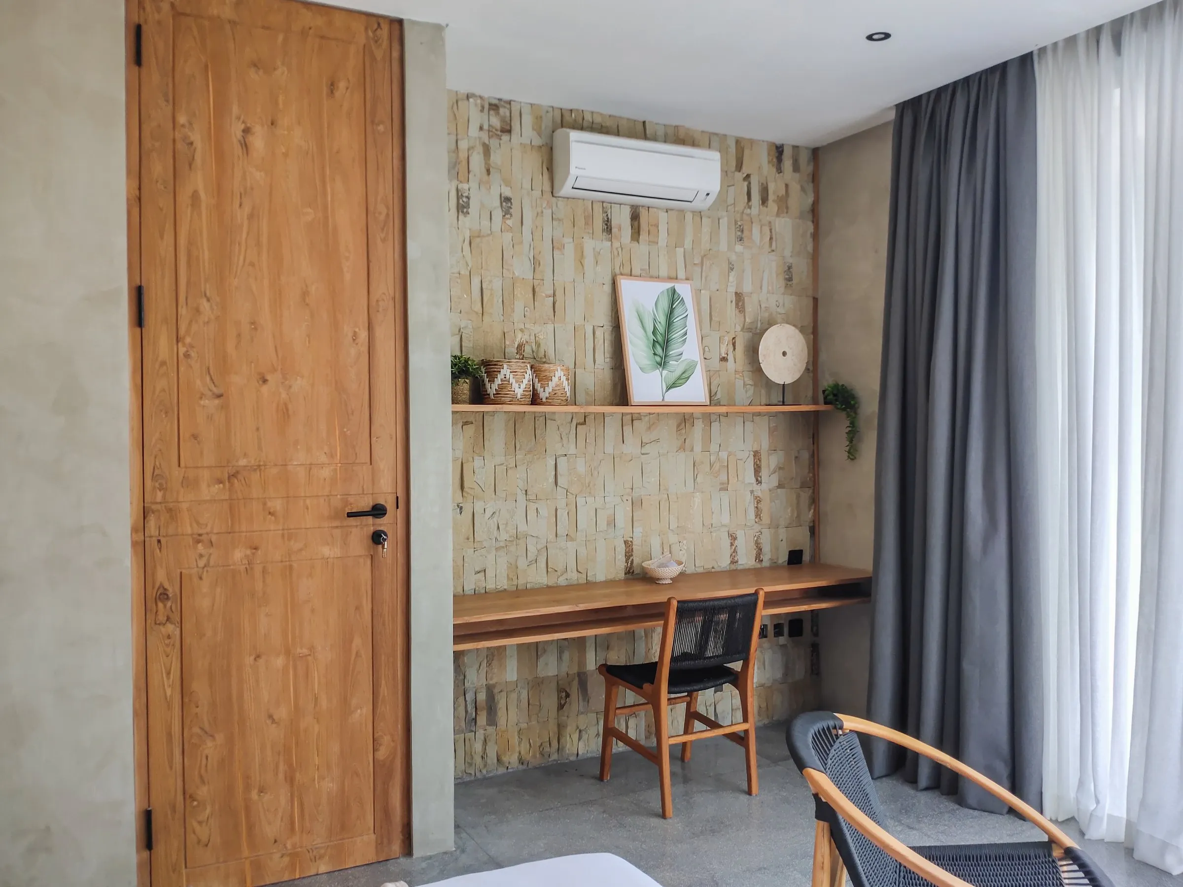 Wall-mounted teak desk and shelf beside a full-height teak door.