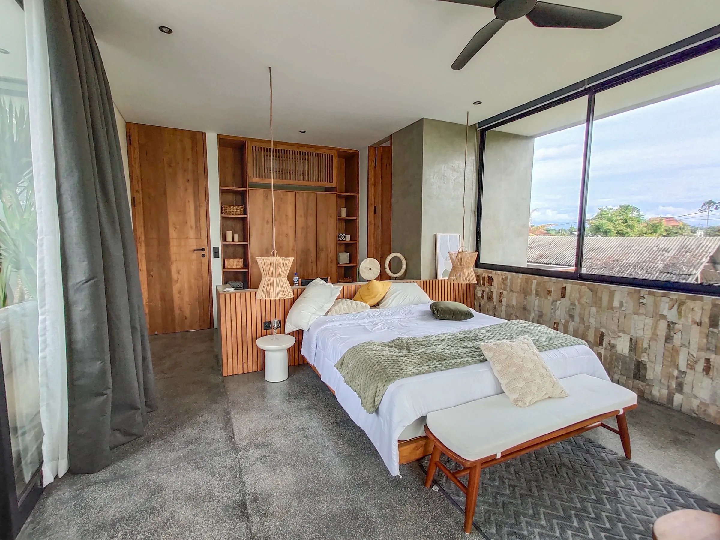 Bedroom with a teak bed frame, bench and built-in shelving.