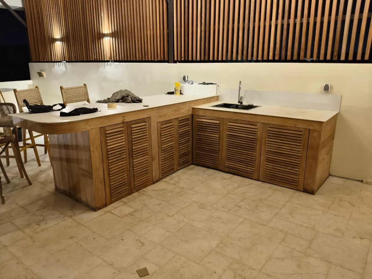 Kitchen with louvred teak doors below a slatted teak wall.