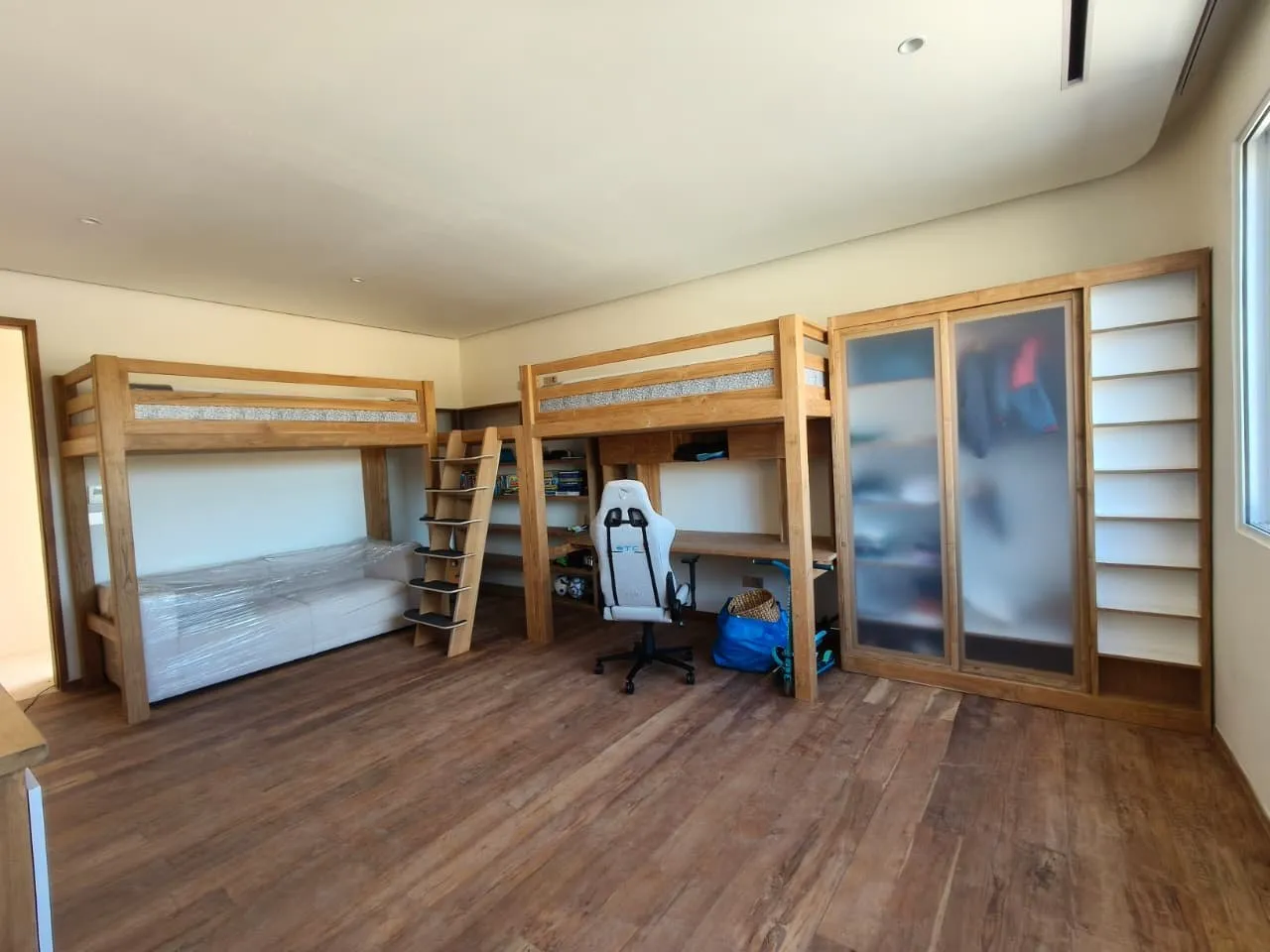 Children's room with teak loft beds, desk and wardrobe.