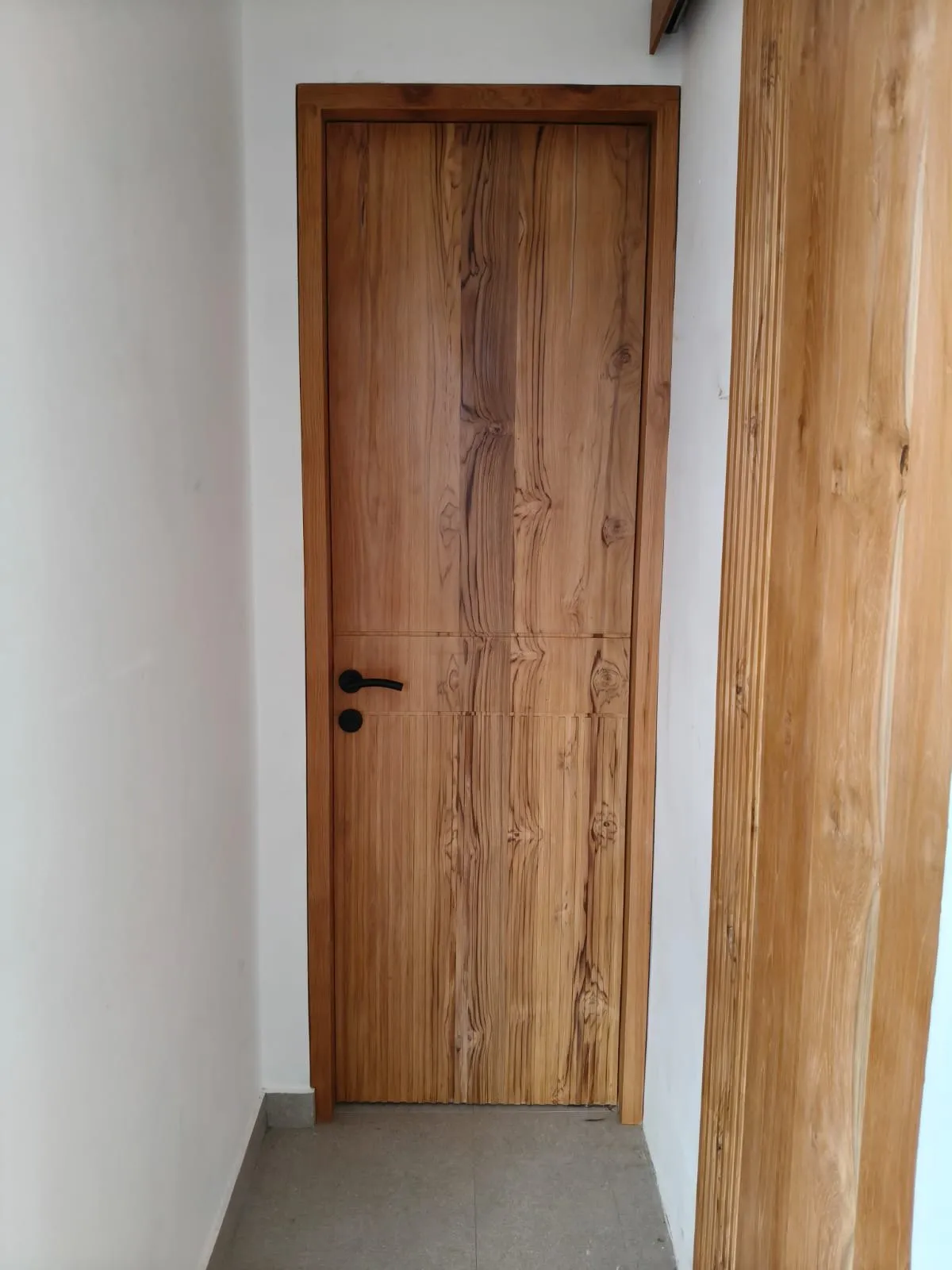 Solid teak door with a strong grain.