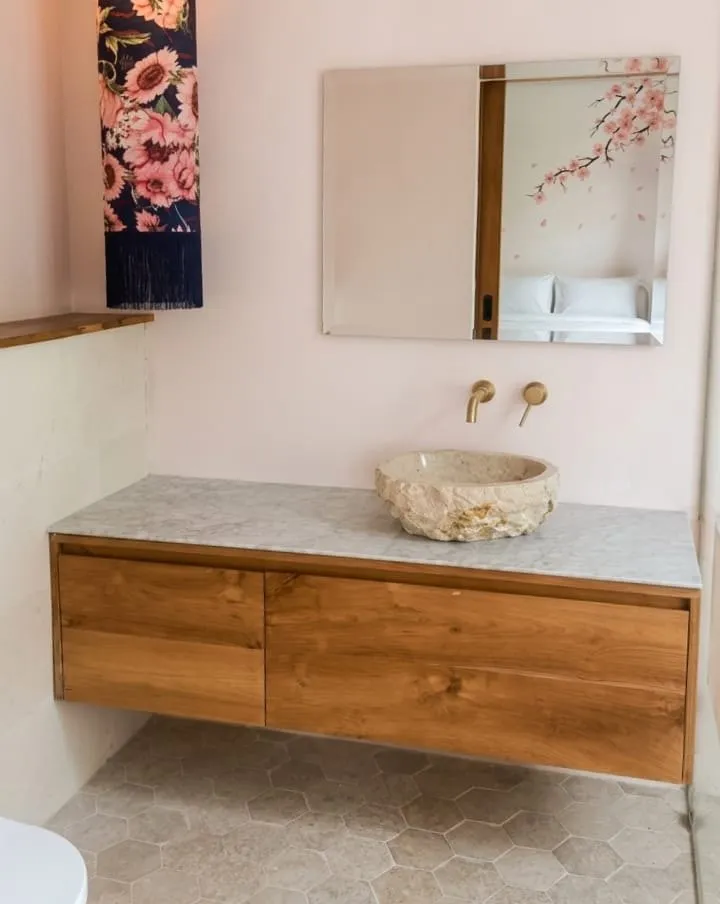 Teak vanity with a stone vessel basin.